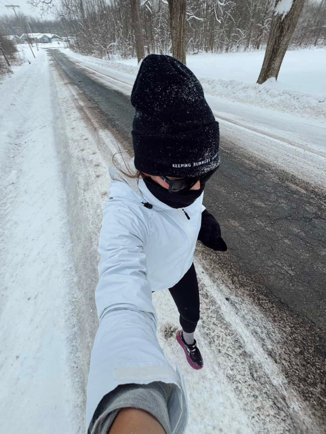 Female Runner running in the snow, "keep runners running" written on her beanie